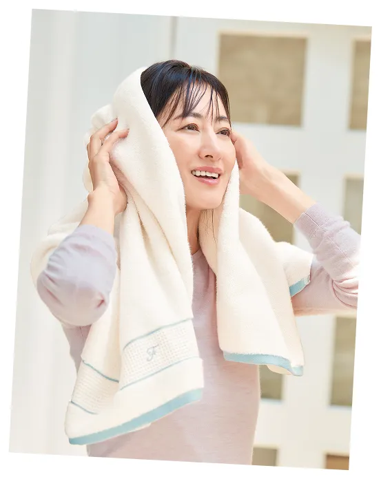 バスタオルで、髪の毛を両手で乾かしている一人の女性